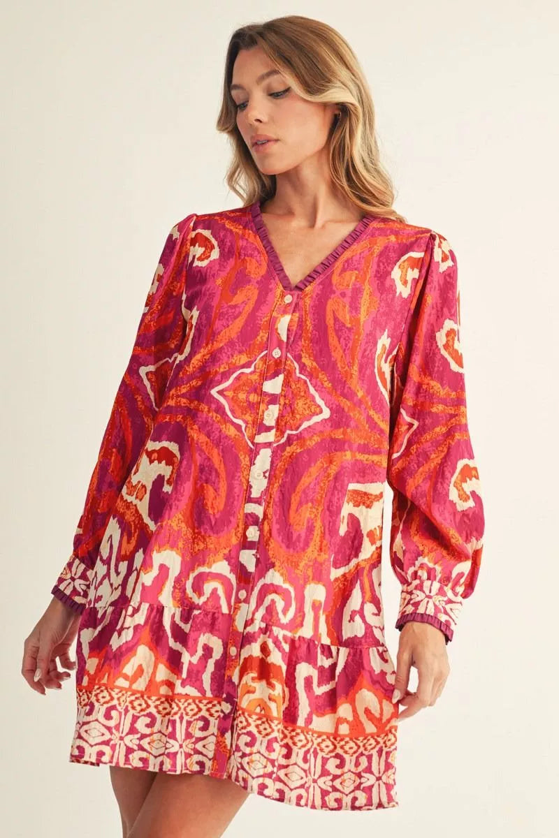 Woman wearing a vibrant patterned dress on a plain background