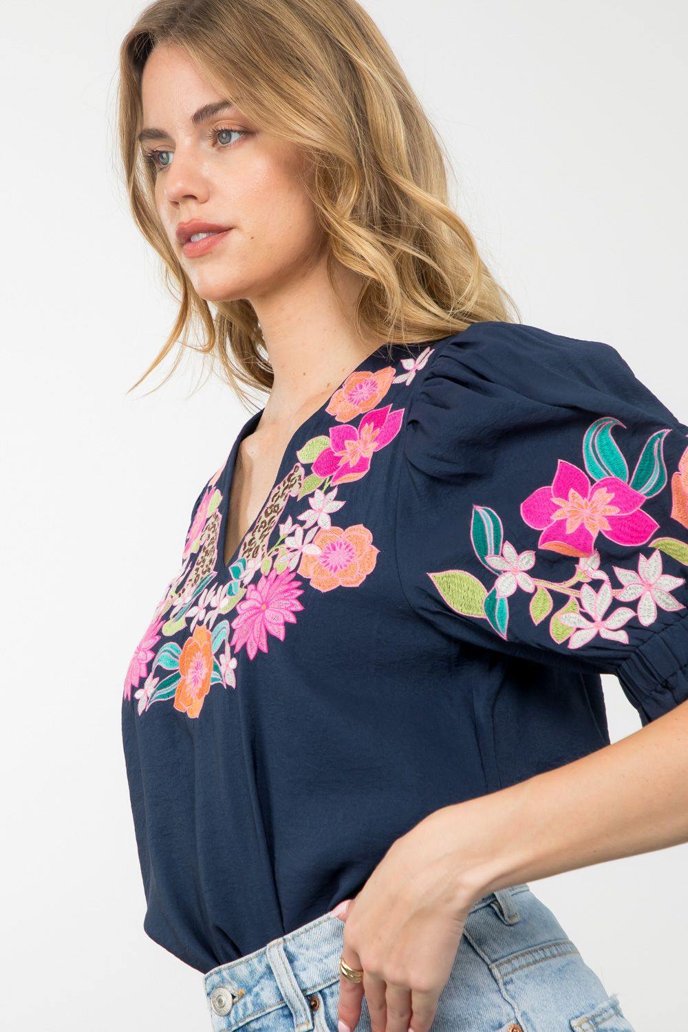 navy blue THML brand top with floral Embroidery at neck and on sleeves cheetah on either side of v neck